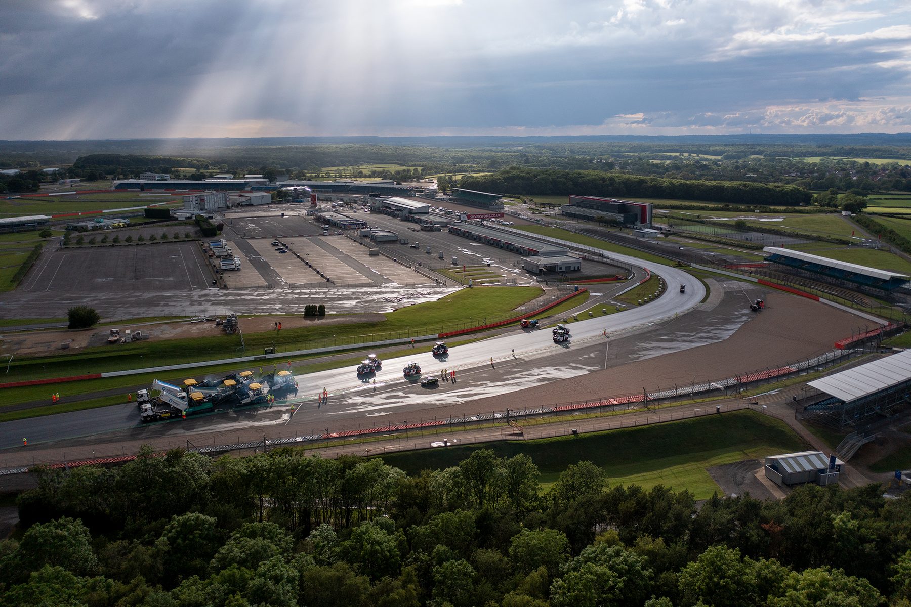 Top-down view of Tarmac pavers and asphalt trucks working across the Silverstone circuit