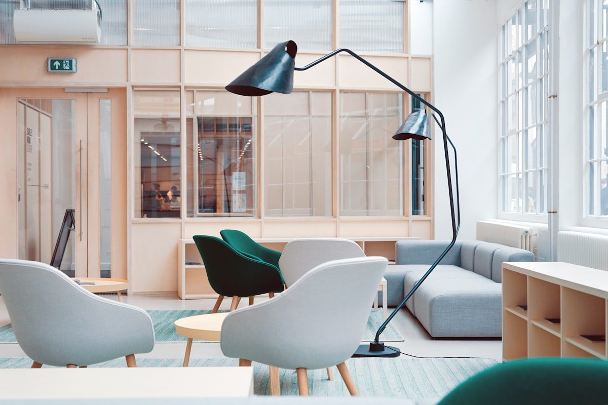 Bright loft-style studio with mid-century seating, a sculptural black floor lamp and warm timber joinery