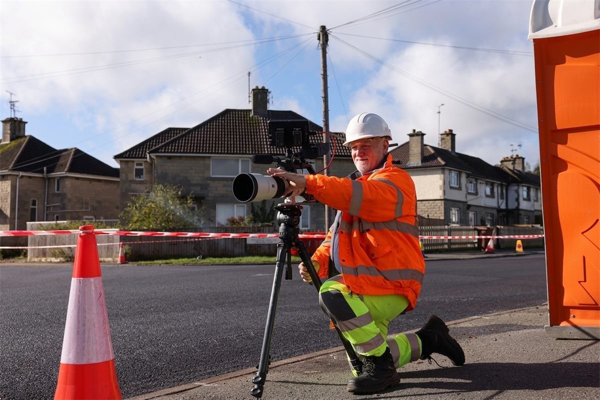 Cinematographer on a tripod capturing behind-the-scenes footage on site