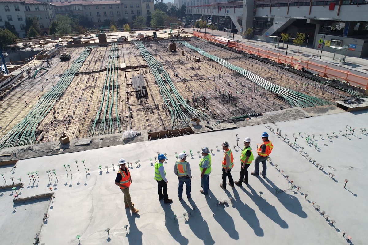 Aerial view of a construction team in high-vis reviewing works across a live rebar deck